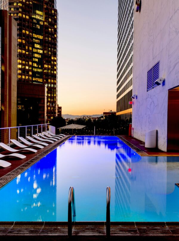 Elegant rooftop pool with cityscape backdrop at sunset, reflecting urban luxury.