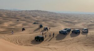 A group of SUVs and people explore the sand dunes in Sharjah, UAE.
