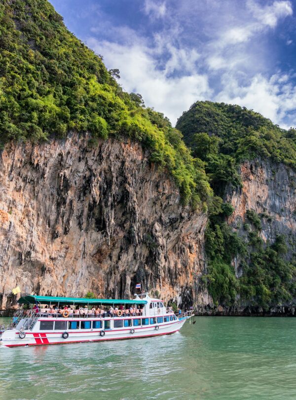 A boat cruise offers breathtaking views of lush cliffs under a bright blue sky.