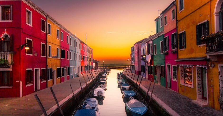 Vibrant facades along Burano's canal with boats at serene sunset. Perfect travel snapshot.