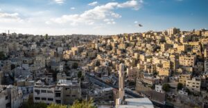Aerial view of Amman's urban landscape with the Jordanian flag waving.
