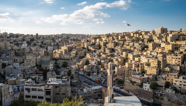 Aerial view of Amman's urban landscape with the Jordanian flag waving.
