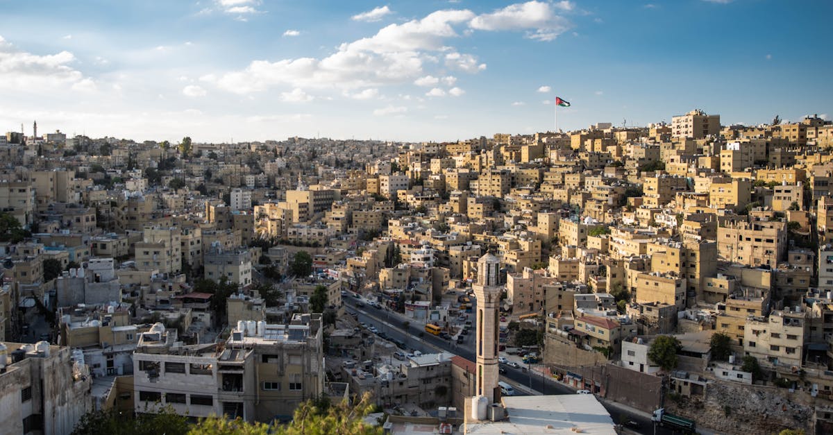 Aerial view of Amman's urban landscape with the Jordanian flag waving.