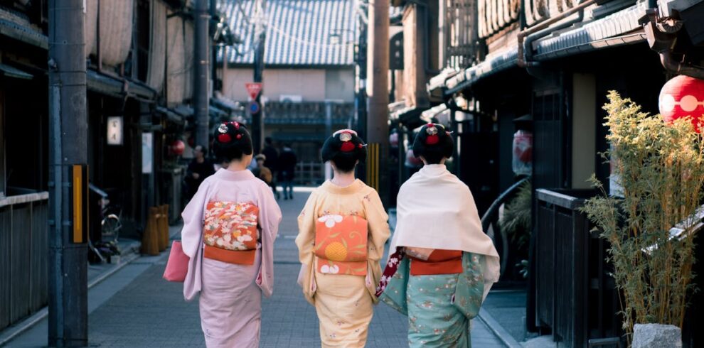 Three women wearing traditional kimonos walk down a historic street in Kyoto, Japan, capturing cultural essence.