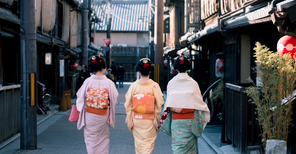 Three women wearing traditional kimonos walk down a historic street in Kyoto, Japan, capturing cultural essence.