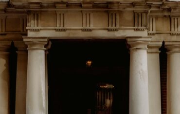 A group of people gathered outside a Canadian embassy entrance featuring a prominent flag.