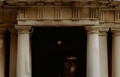 A group of people gathered outside a Canadian embassy entrance featuring a prominent flag.