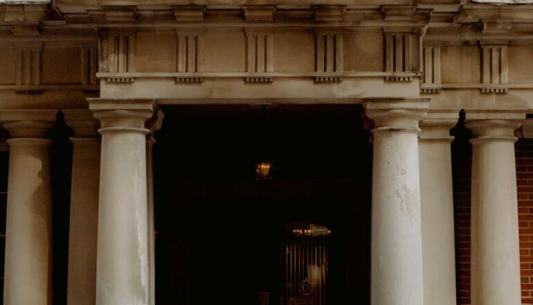 A group of people gathered outside a Canadian embassy entrance featuring a prominent flag.